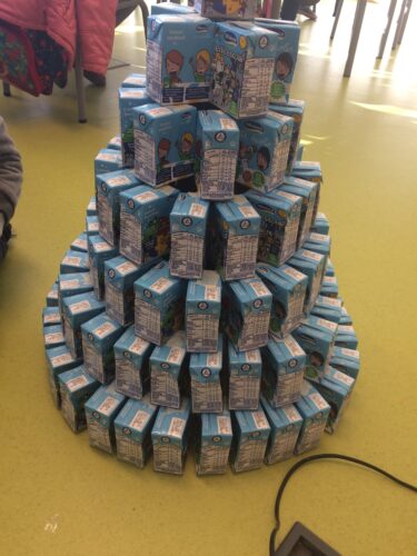 Construção de pirâmide com pacotes de leite escolar, partindo do círculo mais pequeno